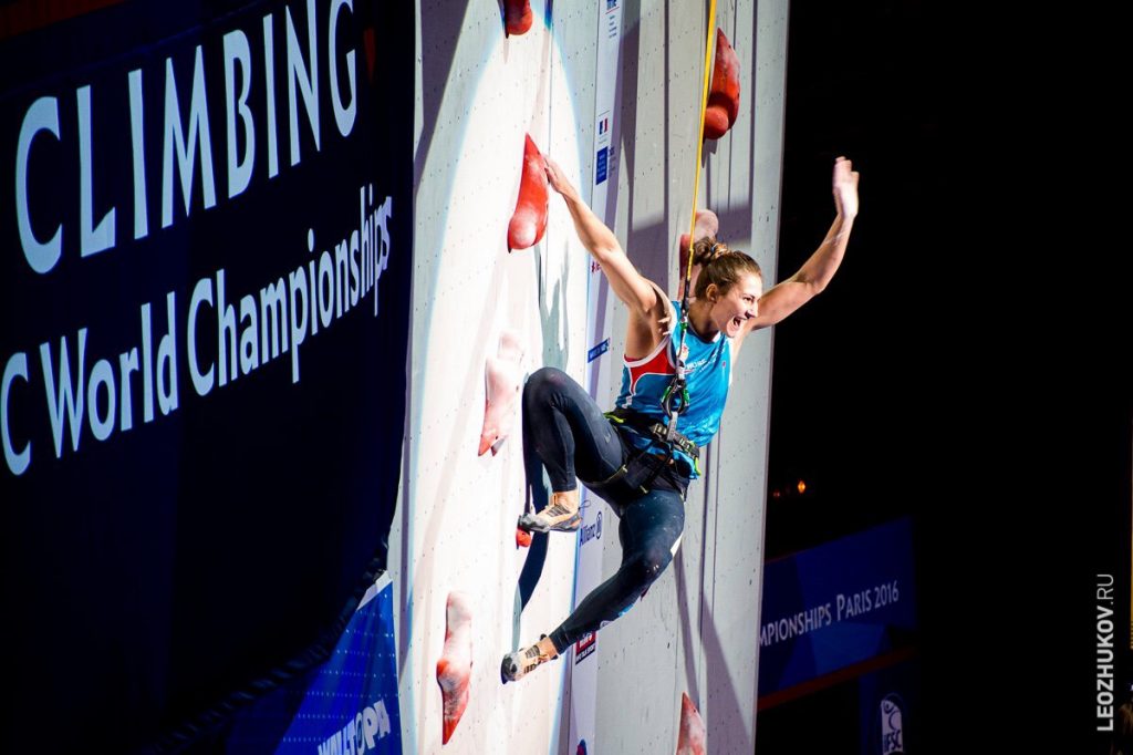 anna tsyganova climbing on indoor wall while cheering
