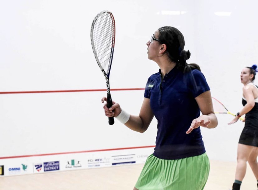 Farida Mohamed strikes the ball, with racquet in hand