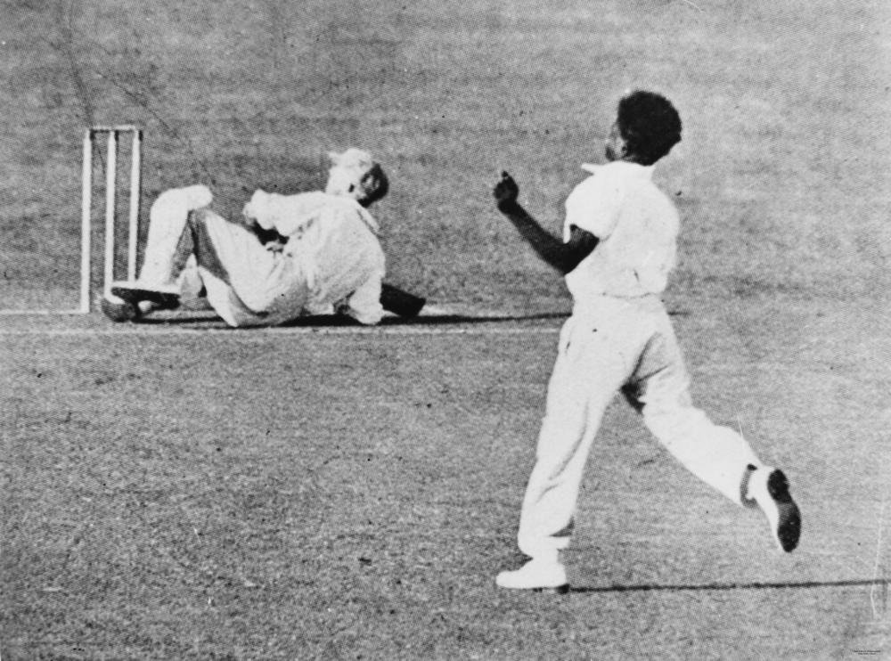 Eddie Gilbert bowling the famous over to Donald Bradman with the Don on the floor