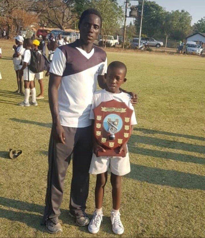 A young Zimbabwe kid with Vusumuzi and a cricket award