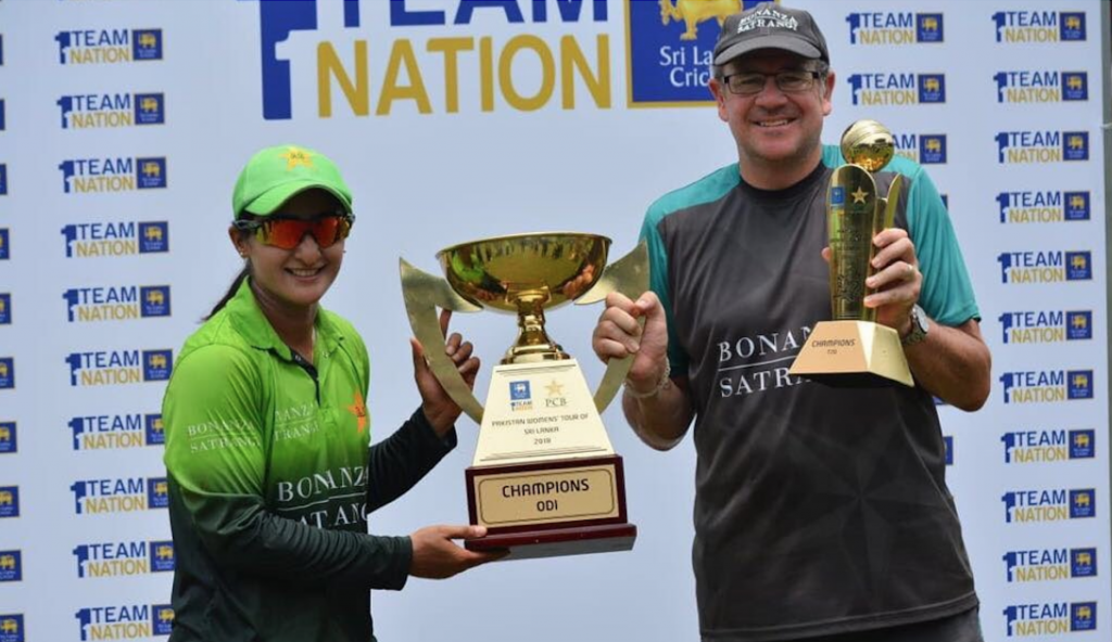 Mark Coles poses with trophies alongside Pakistan captain, Bismah Maroof