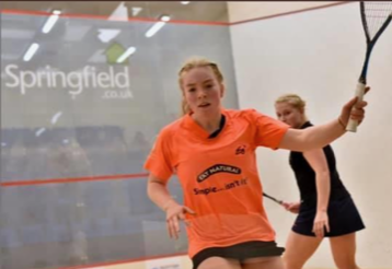 Kartriona-in-orange-shirt Katriona Allen going to hit the ball in squash court, Scotland